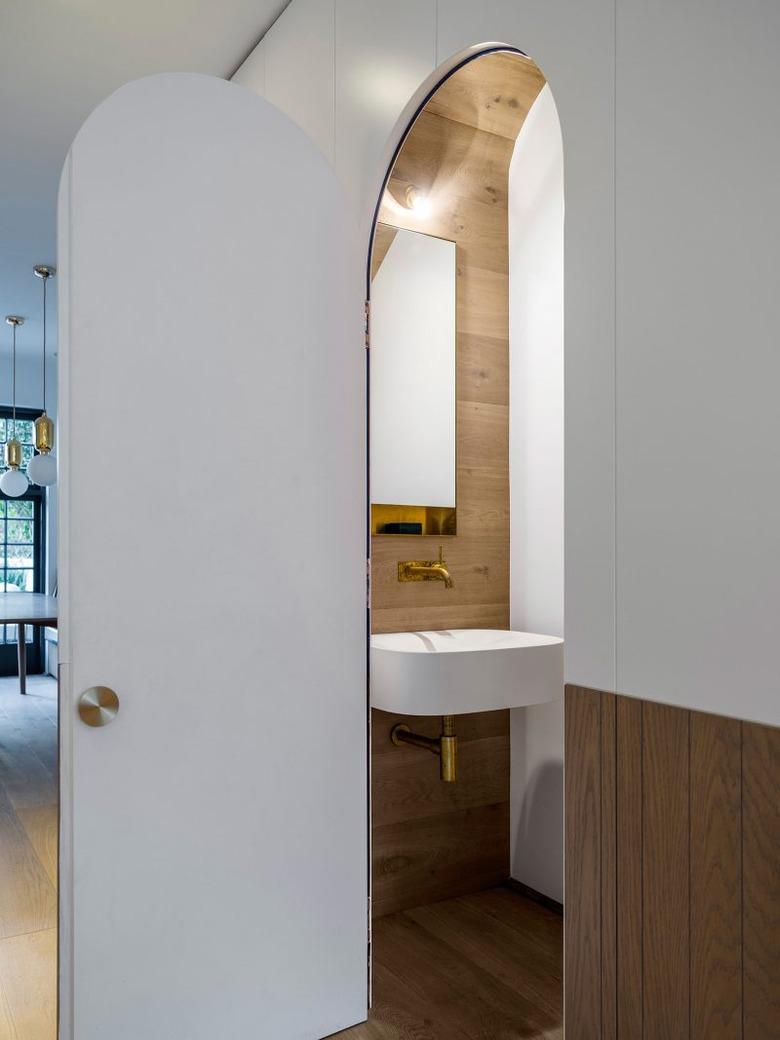 Bathroom under stairs with rounded door and wood paneling