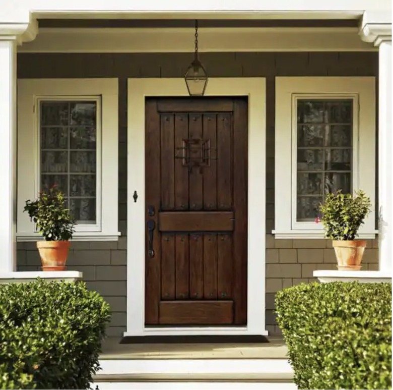 View of the front of a house with a rustic style door and white trim