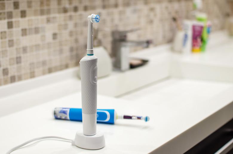 Rechargeable electric toothbrush, close-up against the backdrop of a bathroom in white.