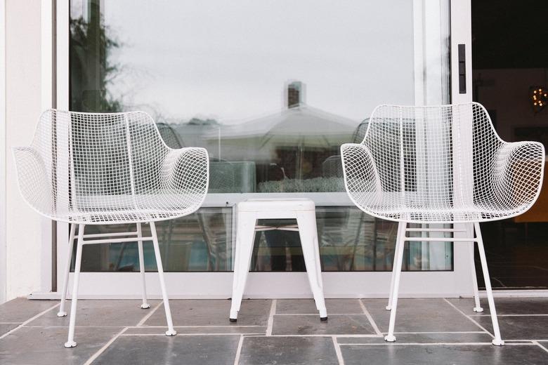 Two plastic modernist style chairs with a small white metal stool in between.