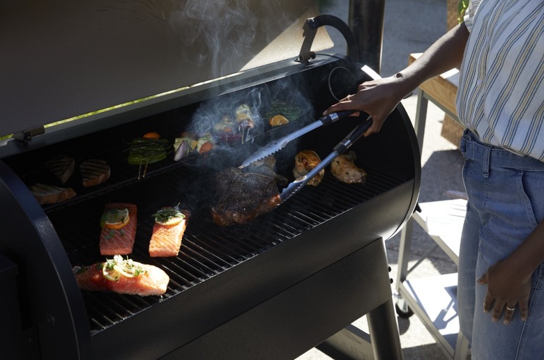 woman grilling salmon and steak outdoors