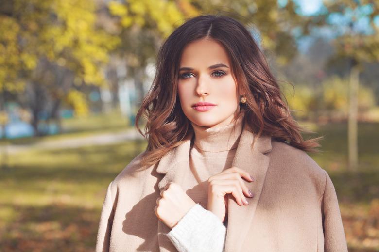 Autumn beauty. Perfect woman in beige coat outdoor. Girl walking in autumn park