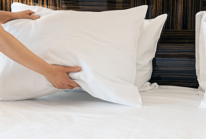 female hands corrected pillow on the bed