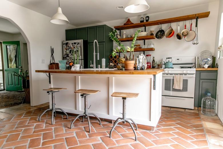 Mexican tile floor in kitchen with green cabinets and wood countertop