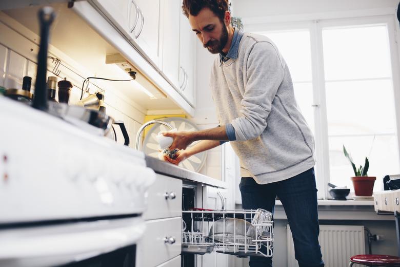 Man cleaning utensils in kitchen at home