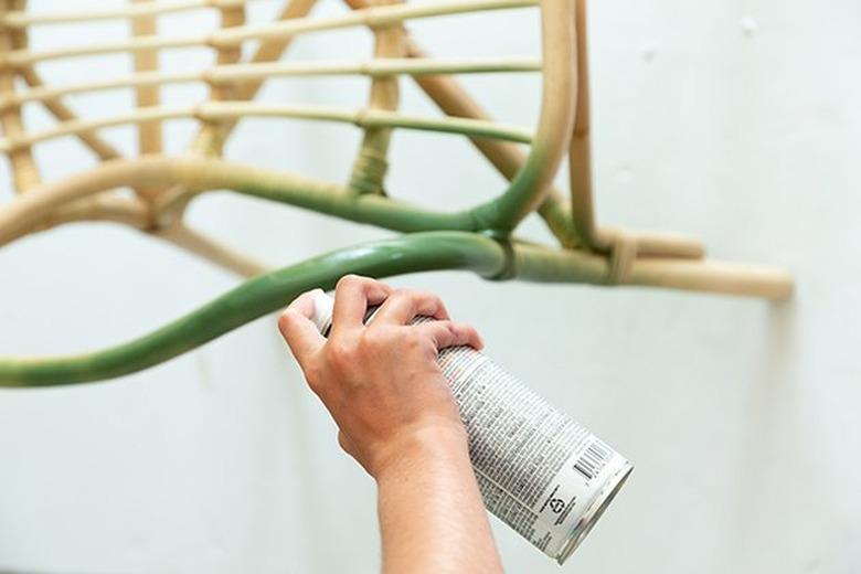 Spray painting rattan chair with green paint.