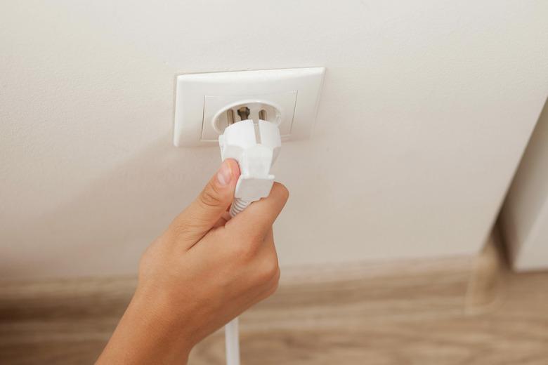 Hand plugging in or out an electric cord into a socket