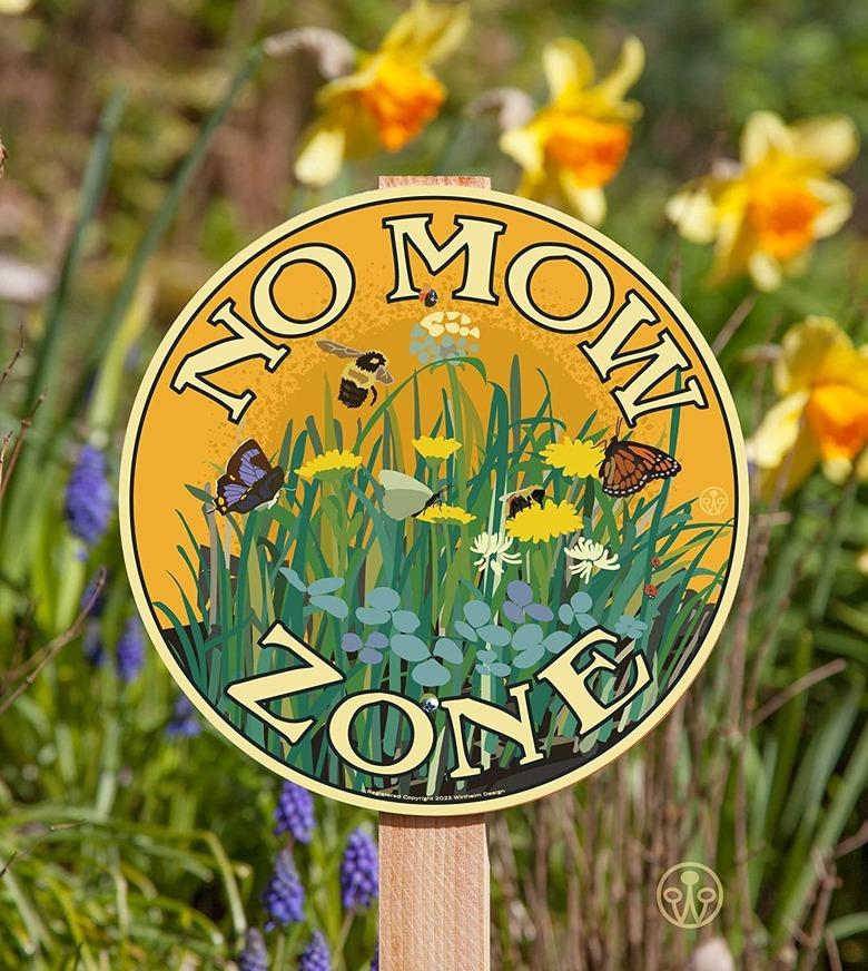 A Now Mow May sign that says "No Mow Zone" with an illustration of bees, butterflies, and various flowers in a yard.