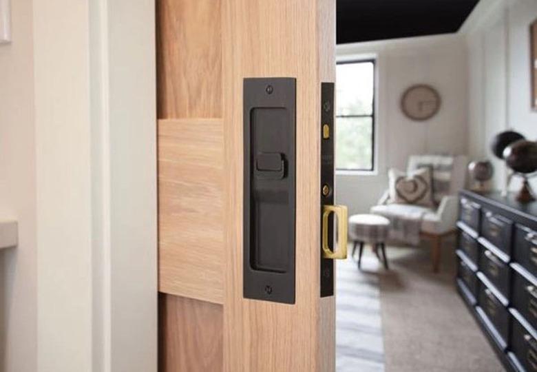 A wood pocket door with black hardware slightly opened