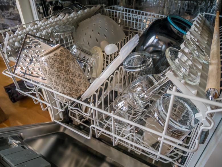 Open dish washer is done. Clean glasses and kitchen ware. Modern style.