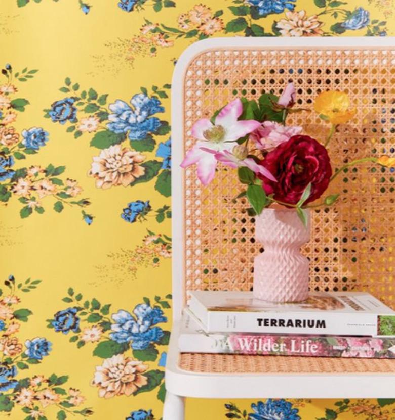 yellow floral wallpaper with chair and books nearby