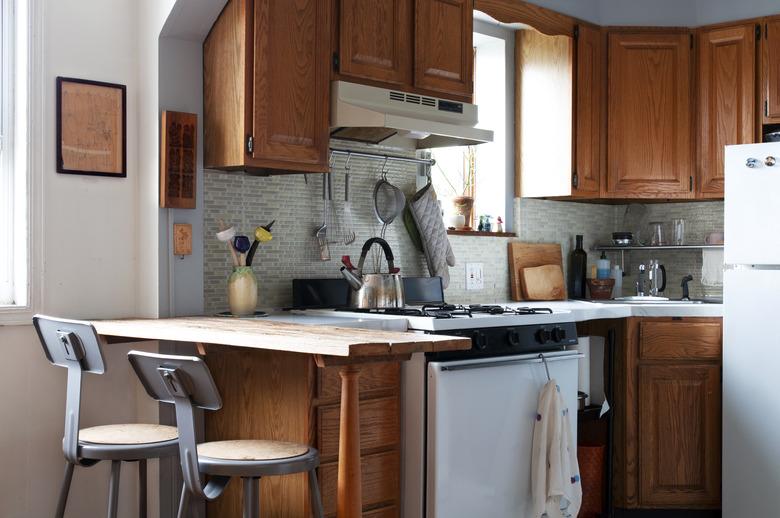 small kitchen with wood cabinetry and glass backsplash