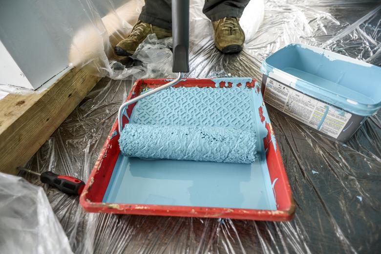 Preparing to painting wall in house blue paint by paint roller.