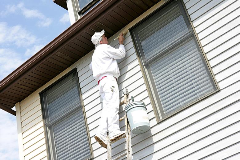 House Painter On Ladder Leaning Against House