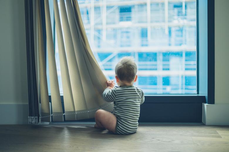 LIttle baby playing with curtain in apartment