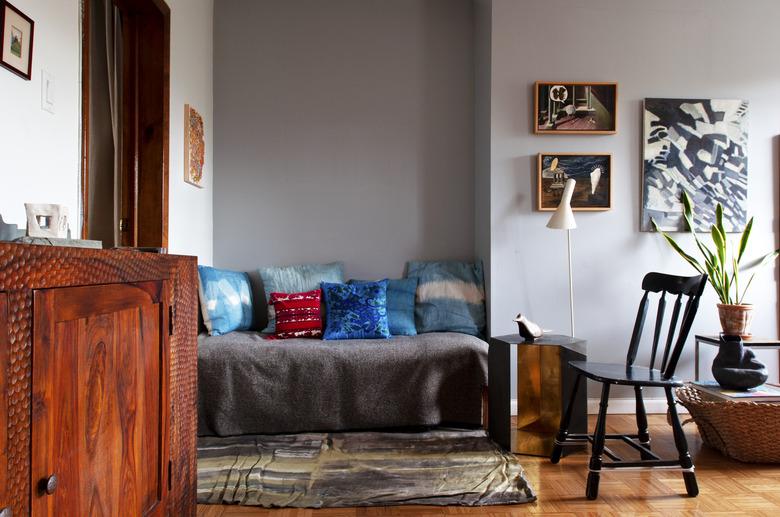 cozy nook with colorful pillows, art wall, and hardwood floors