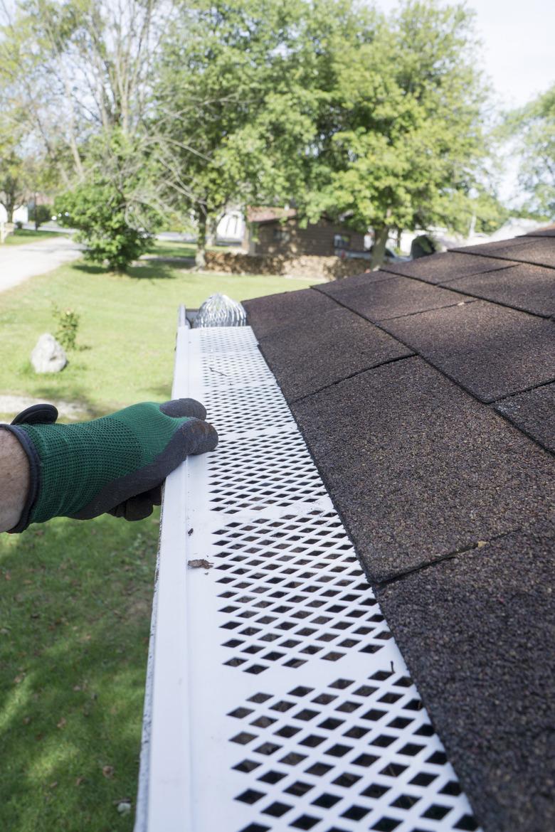 Contractor Checking Installation Of Plastic Leaf Guards