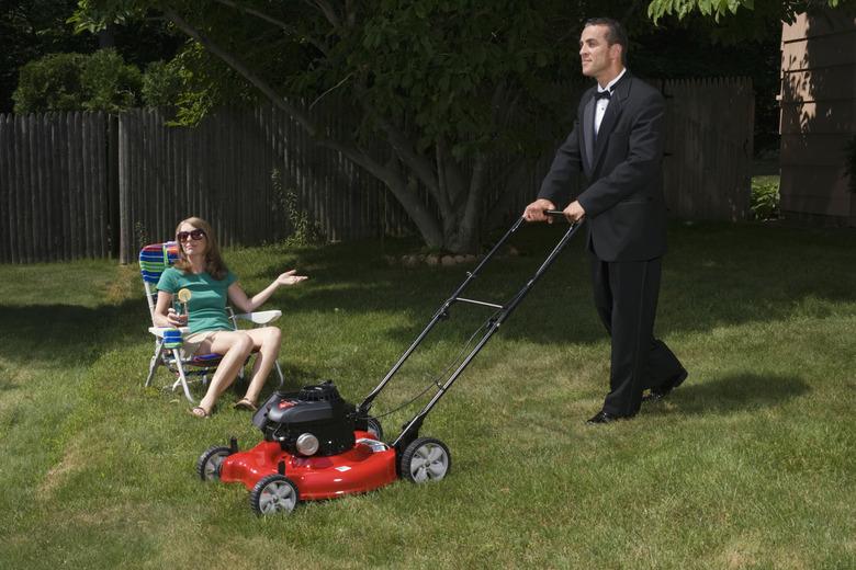 Mature woman sitting in deckchair, butler mowing grass