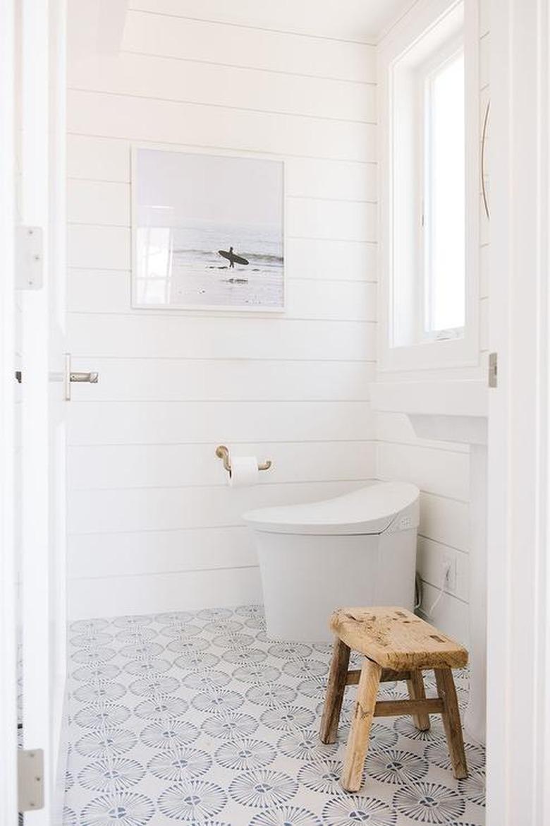 modern toilet in bathroom with white shiplap and pattern floor tiles