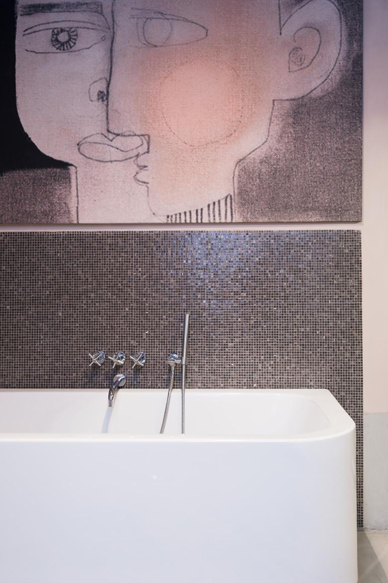 mosaic tile bathroom backsplash idea at bathtub with oversize artwork above