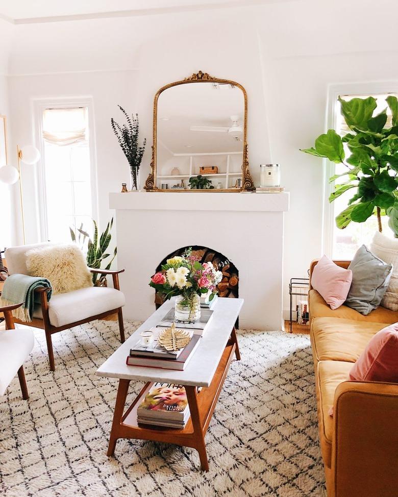 natural decor in white living room with fireplace and mirror on mantel