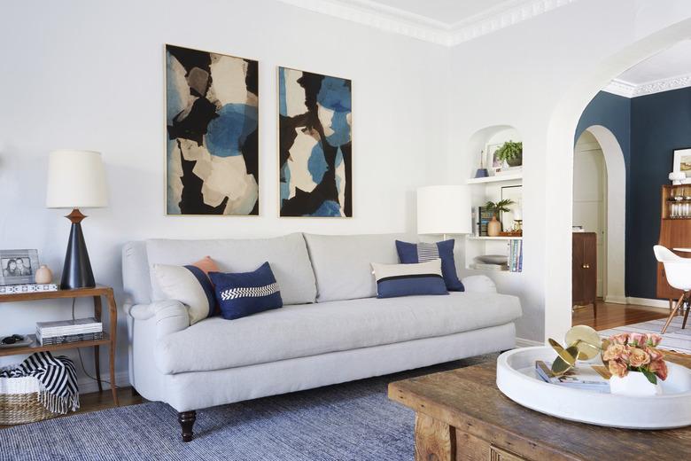 navy blue living room idea designed by Emily Henderson with blue accent pillows on sofa