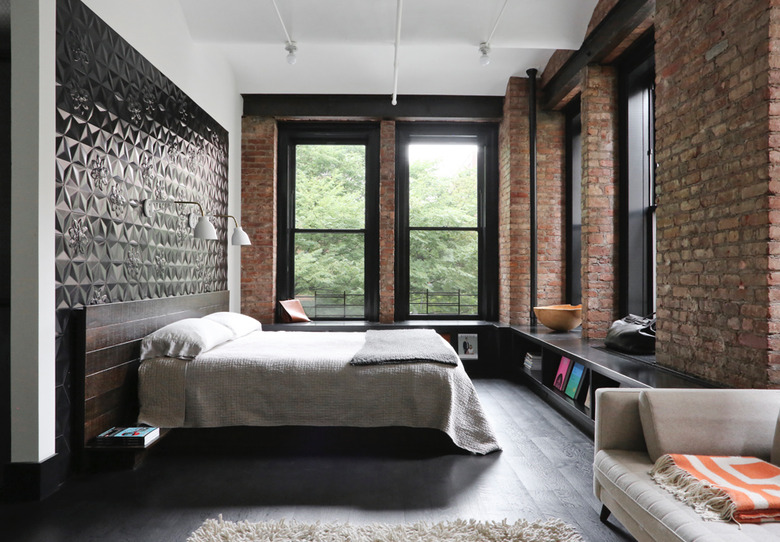 black and white bedroom idea with exposed brick and dark wood flooring