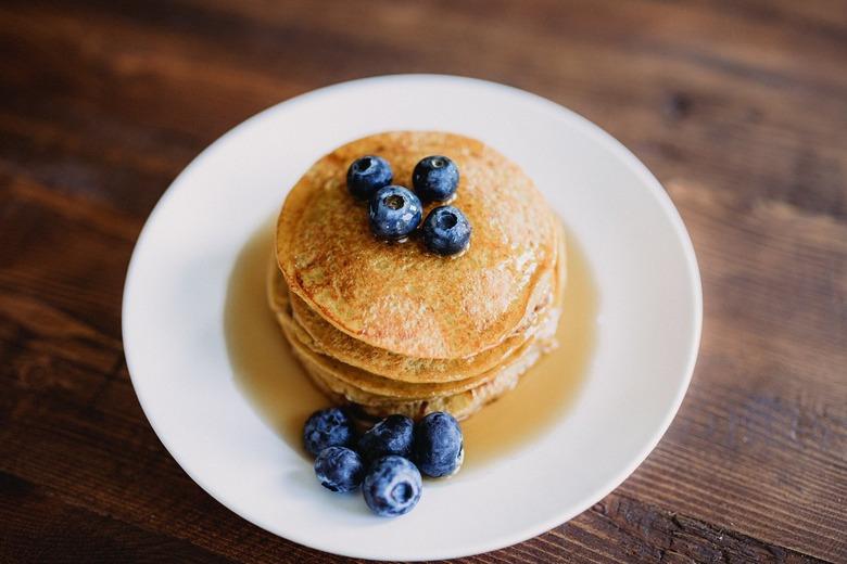 Pancakes with maple syrup and blueberries on a white plate