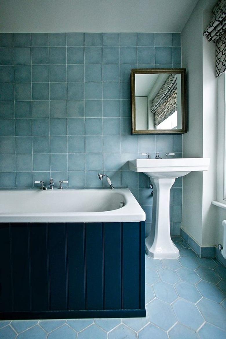 Pedestal Sink Storage Ideas in Bathroom with white pedestal sink, blue tile on walls and floors, medicine cabinet, navy blue wood siding on bathtub.