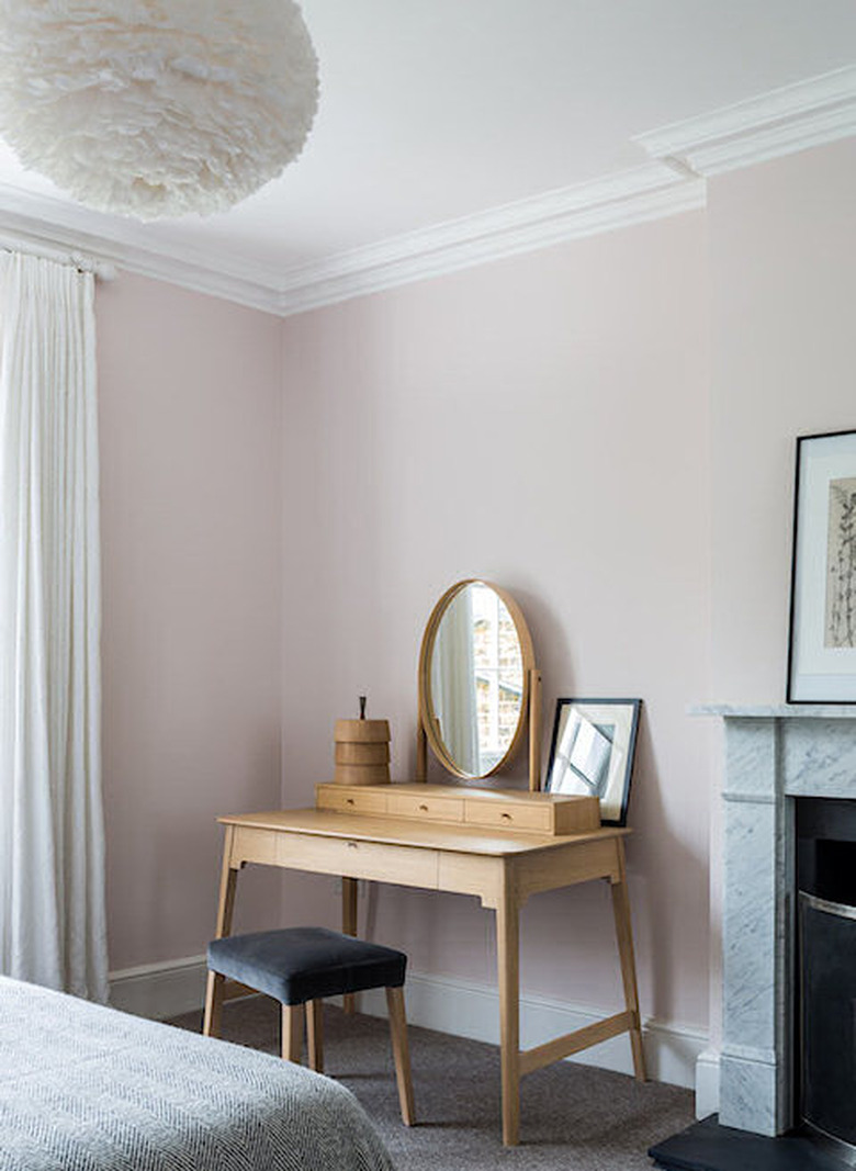 pale pink bedroom with wood vanity table and fireplace