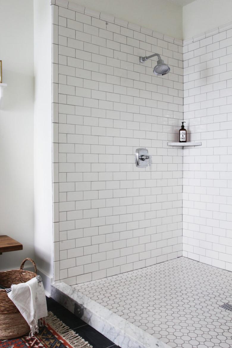 Polished chrome shower fixtures in subway tile with dark grout