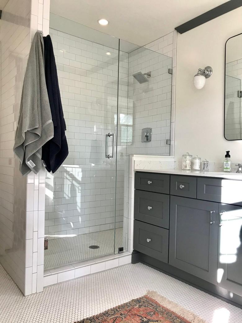 Polished chrome shower fixtures and hardware in gray and white bathroom