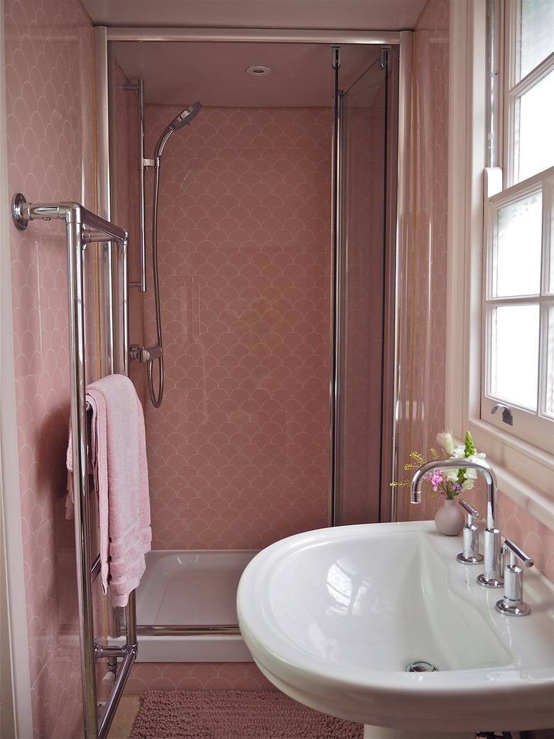 Polished chrome shower fixtures in pink tile shower