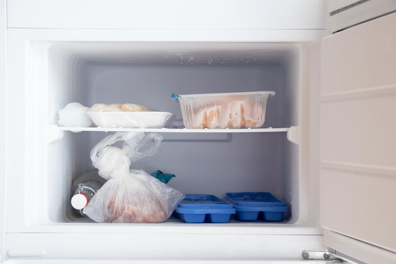 Freezer in the refrigerator, inside a tray with ice and meat and a bottle of vodka, food in the freezer in the kitchen