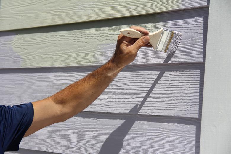 Close-up of a man's hand painting exterior of house