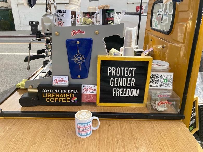 View of a yellow coffee cart with mugs and decor, including a sign that reads 