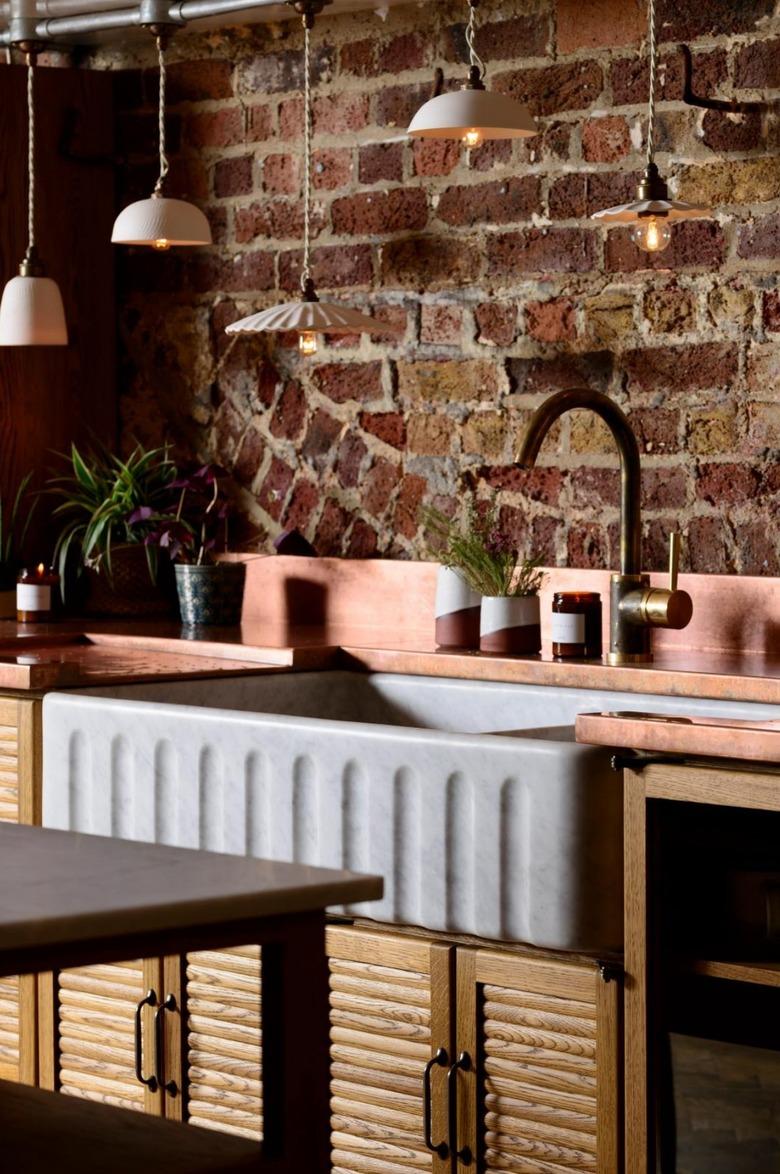 wood reeded cabinets in rustic kitchen with brick wall