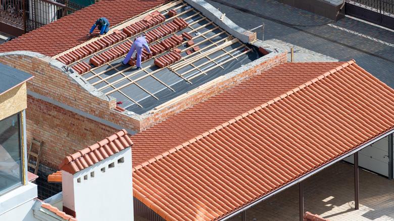 Roofers working on rooftop, install new tile