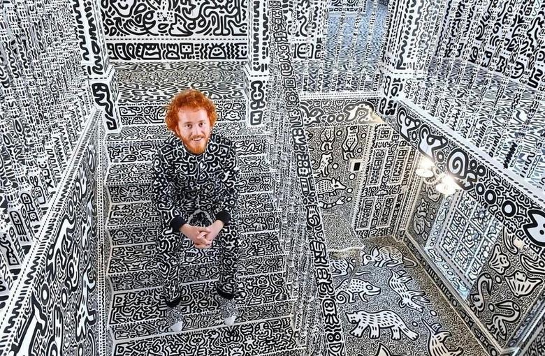 Sam Cox sitting on his doodled stairs in his doodled home wearing a doodled jumpsuit.