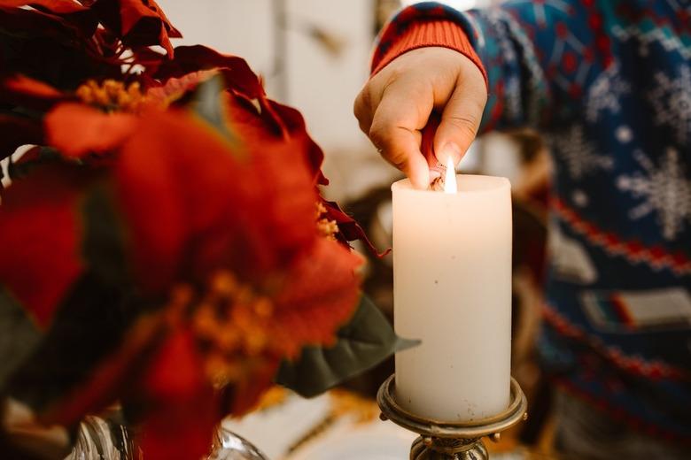 Children lighting a handle next to poinsettia flowers