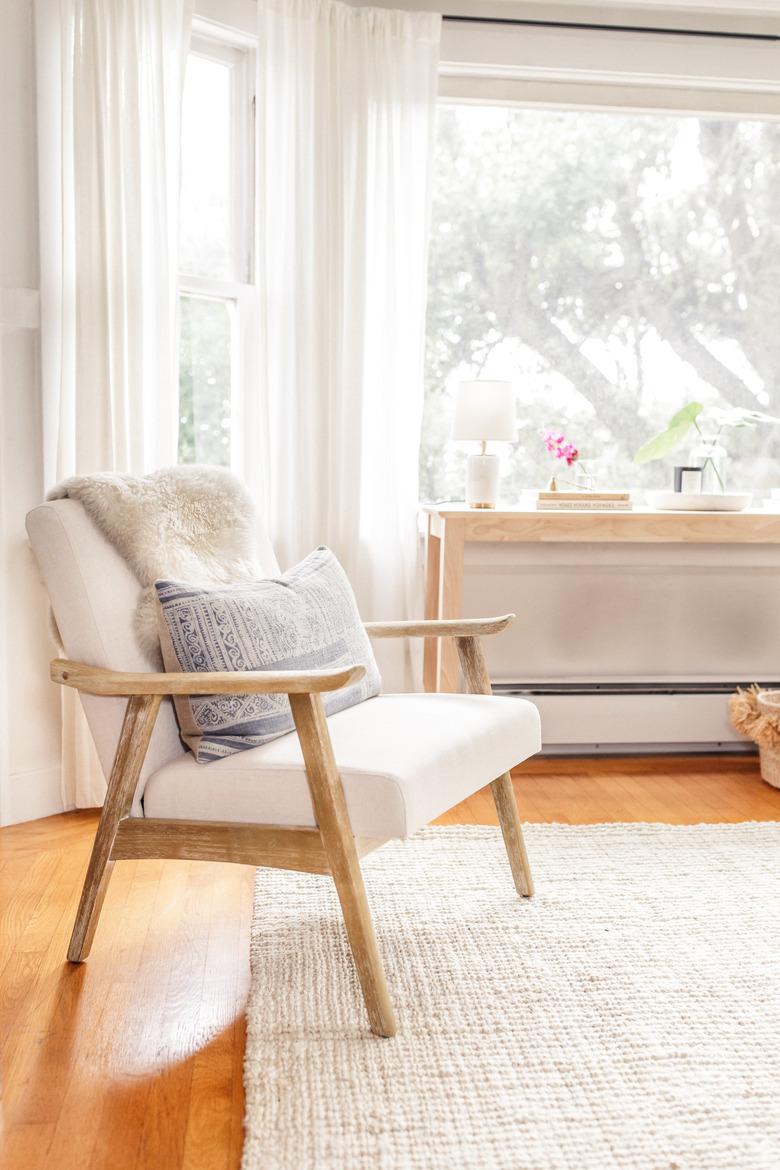 Scandinavian living room with white chair draped with faux fur and sheer drapery