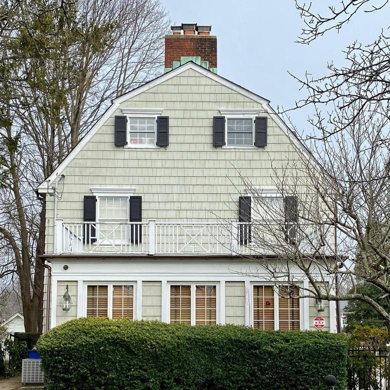 The Amityville Horror house exterior. It's an off-white with black shutters and a white balcony.