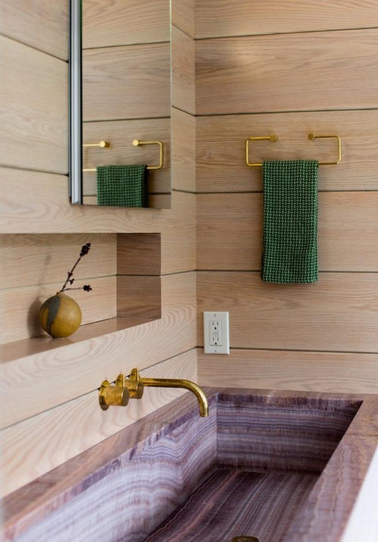 Bathroom sink area with light wood shiplap, pink marble sink.