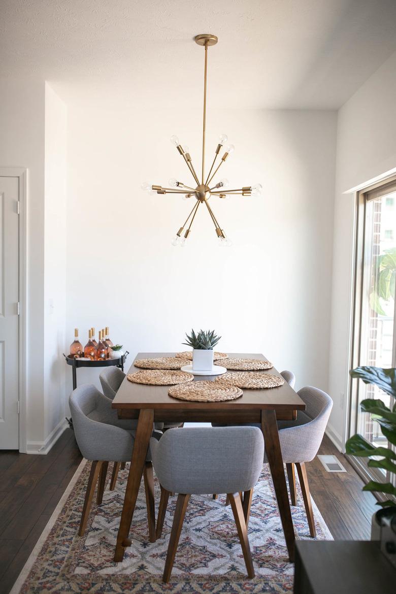 Small dining room storage idea with midcentury chandelier and bar cart