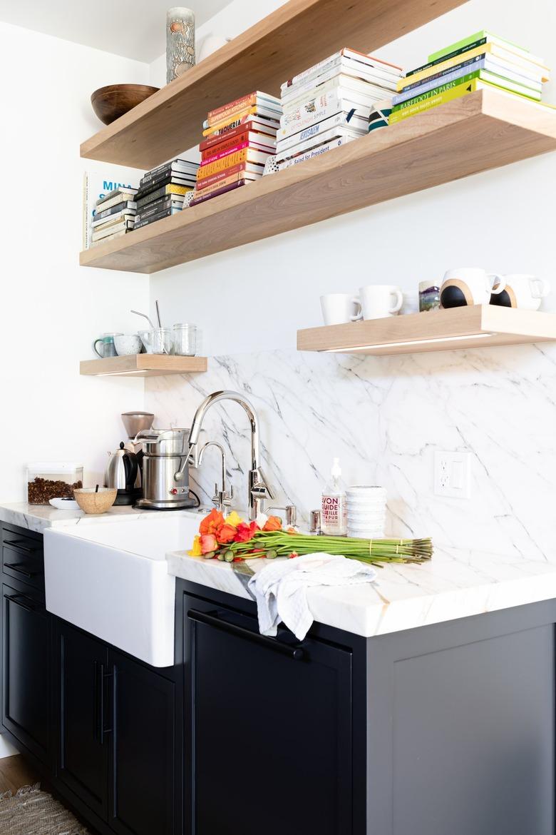 White walled kitchen with gray cabinets, granite countertops and wood shelving