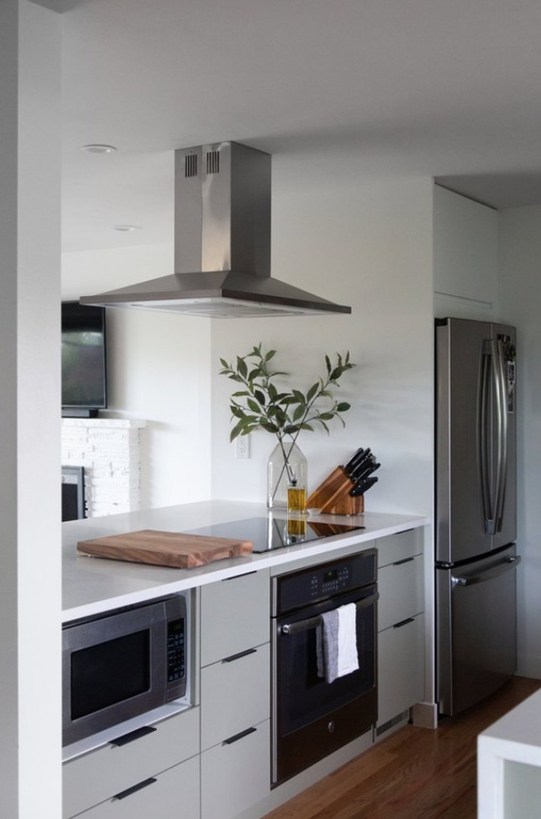 Small kitchen with microwave under counter, stainless hood.