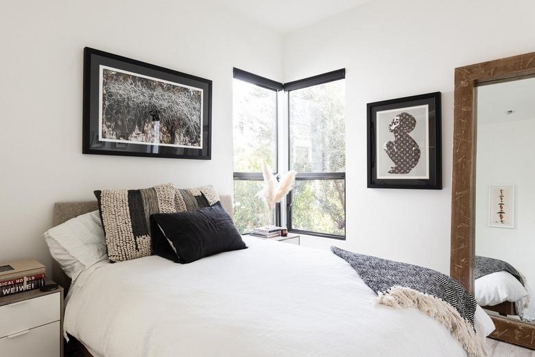 White-walled bedroom with a corner window and gray-black accents