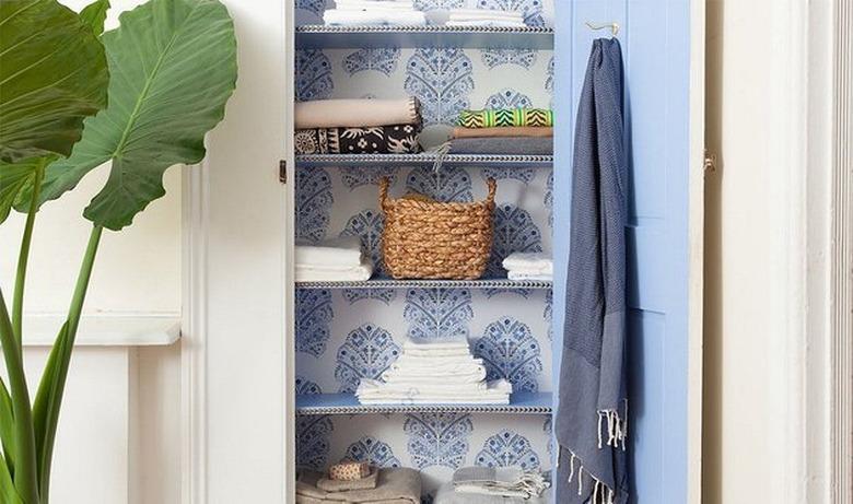 closet with blue patterned wallpaper with towels and basket