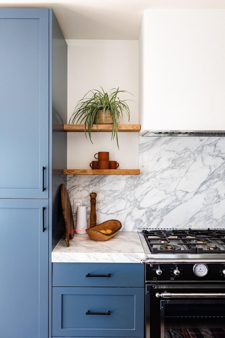 blue and white kitchen with stove hood vent and marble backsplash