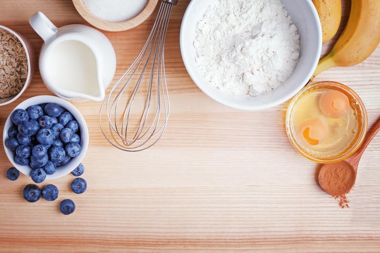 Ingredients for blueberry muffins preparation on wooden table, top view.